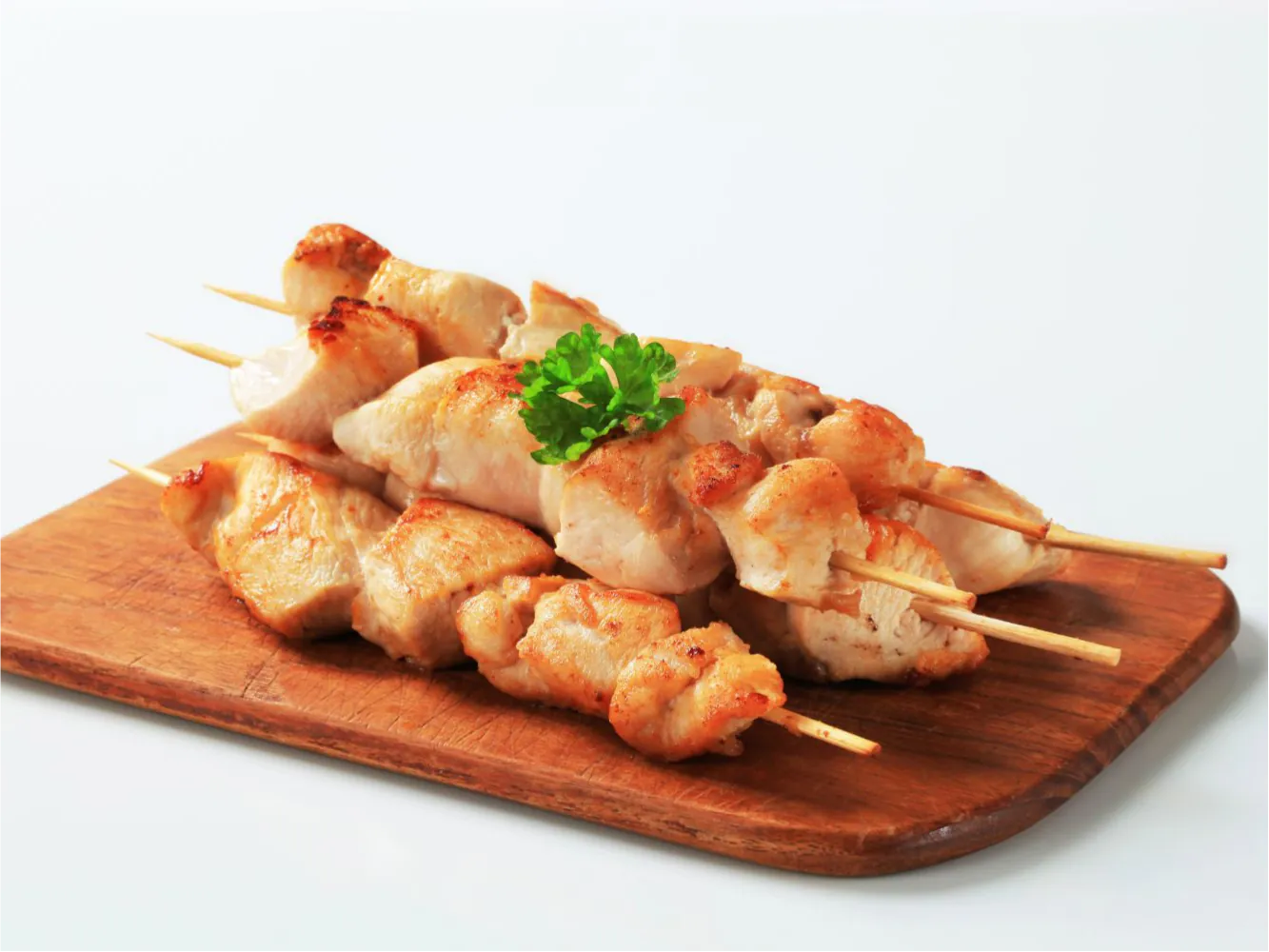 Juicy grilled chicken skewers with parsley garnish at Fuzhou Milk Tea, a Barbecue & Milk Tea Shop in Brooklyn
